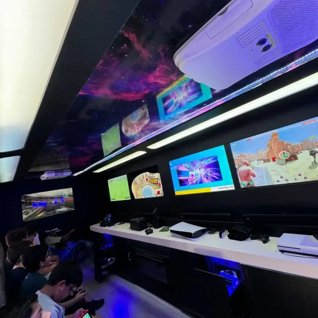 Inside the gaming truck with five HD screens lit up under a galaxy LED ceiling