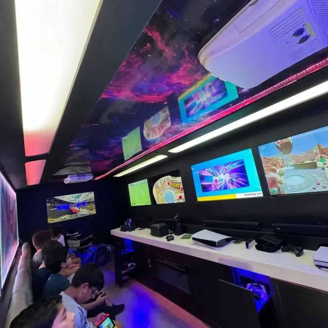 Wide view of the mobile gaming truck interior with multiple screens running Fortnite, Rocket League and racing games